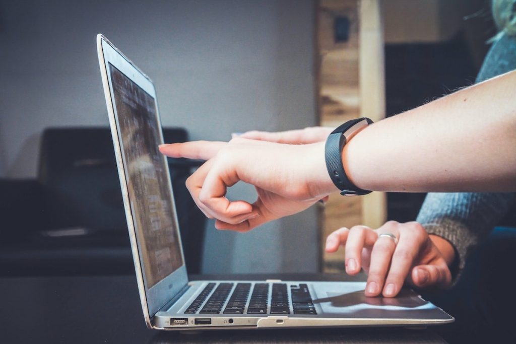 Law enforcement officers pointing to evidence management software on their laptop screen.